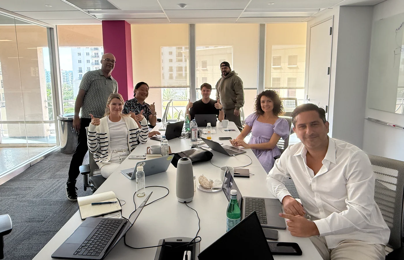 Seven people gathered around a table with open laptops.